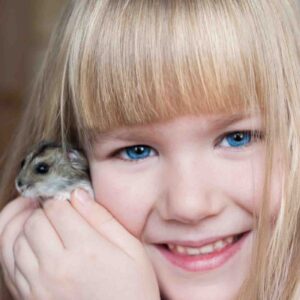 A child cuddling with a hamster
