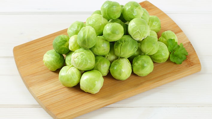 A cutting board with raw Brussels sprouts arranged on it